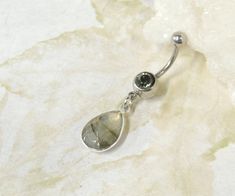 Labradorite Belly Button Ring Perfect for showing off your beautiful belly! Belly ring features a silver plated faceted labradorite gemstone teardrop that dangles from a 14g surgical steel barbell with your choice of clear crystal gem or black diamond gem. Labradorite stone measures 10 x 14mm. Belly button ring measures 1 3/4 inches long total length. Barbell is 14g surgical steel. Top ball measures 5mm, bottom ball measure 8mm. For Belly Button Rings: https://www.etsy.com/shop/AllAboutClass?sec Crystal Belly Button Ring, Belly Button Rings Silver, Belly Button Jewellery, Silver Teardrop Belly Rings For Gifts, Belly Button Rings Dangle, Ring Teardrop, Bellybutton Piercings, Titanium Belly Ring, Belly Button Jewelry