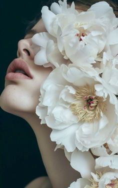 a woman with flowers in her hair is looking at the camera while she has her eyes closed