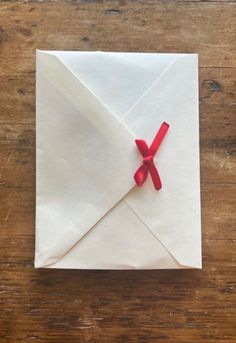 an origami envelope with red ribbon tied around it on a wooden table top