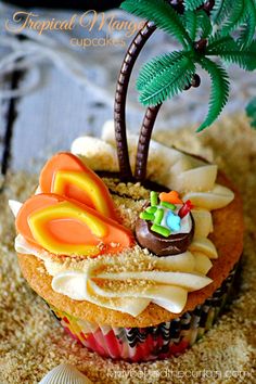 a cupcake decorated with an image of a palm tree and beach scene on top