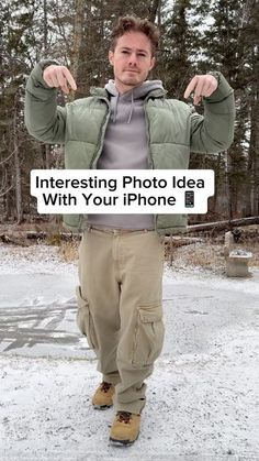 a man is standing in the snow with his hands up and pointing to the camera