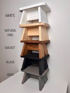 a stack of different types of wooden furniture on top of a white table next to a gray wall