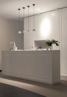 a white reception desk with flowers and laptop on it