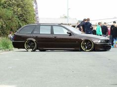 a brown car parked on the side of a road next to a group of people