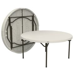 a white table sitting next to a black and white wall mounted round mirror on top of a metal frame