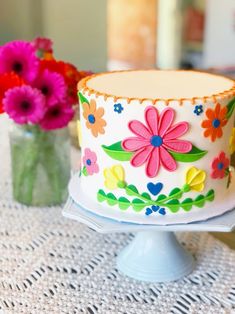 a decorated cake sitting on top of a table next to vases filled with flowers