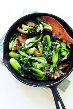 a skillet filled with mushrooms and broccoli on top of a white table