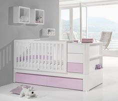 a white crib with pink drawers and a stuffed animal on the floor next to it