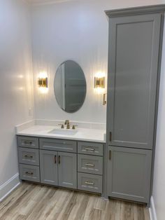 a bathroom with two sinks and cabinets in the corner, one is white and the other is gray