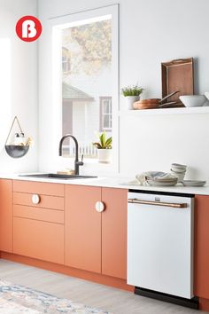 an orange and white kitchen with wooden cabinets, dishwasher, sink and window