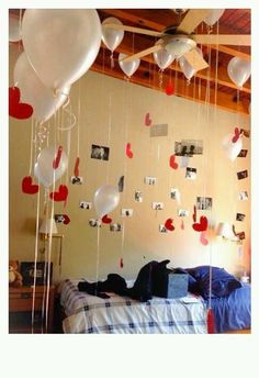 balloons are hanging from the ceiling in a room with a bed and pictures on the wall