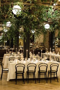 the tables are set with white tablecloths and black chairs, surrounded by greenery