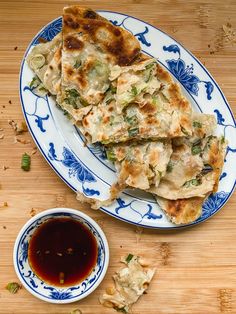 some food is sitting on a blue and white plate next to a bowl of dipping sauce