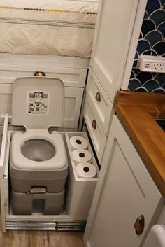 a small bathroom with a toilet in the corner and some rolls of toilet paper next to it