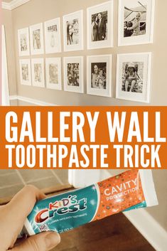 a person holding a tube of toothpaste in front of pictures on the wall