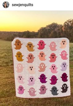 there is a quilt made to look like pacman heads on the grass with trees in the background