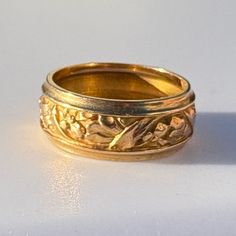 two gold wedding bands with flowers and leaves on the sides, set against a white background