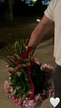 a man holding a bunch of flowers in his hand with a heart on the side