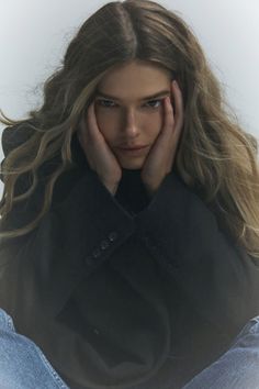 a woman with her hands on her head and looking at the camera while sitting down