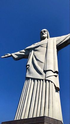 the statue of christ stands tall in front of a blue sky