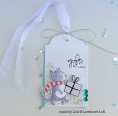 a tag with a cat holding a present on it's side and a white ribbon