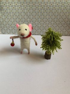 a toy mouse standing next to a small tree