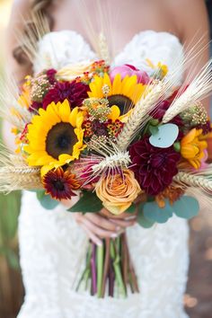 a bride holding a bouquet of sunflowers and other flowers