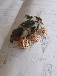 four crocheted hearts are sitting on top of an open book with drawings in the background