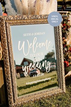 a wedding welcome sign is displayed in front of some flowers and pampaste grass