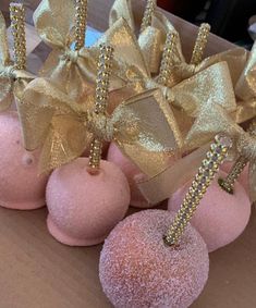 some pink and gold donuts are in a box with bows on them as decorations