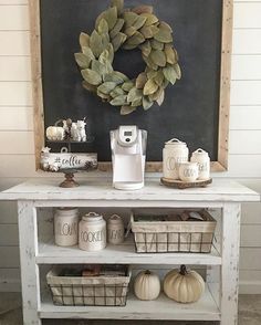 a white table topped with baskets filled with pumpkins next to a chalkboard wall