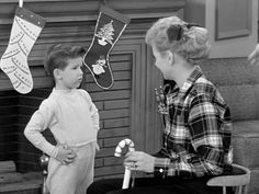 two young boys standing next to each other in front of stockings and stockings hanging from the fireplace