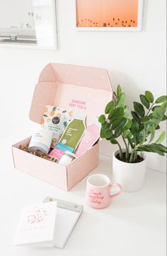 a pink box with some items in it on a table next to a potted plant