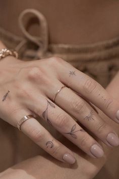 a woman's hand with three different tattoos on her fingers and two other hands