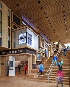 people are walking up and down the stairs in a building with wood paneled walls