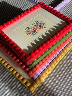 a stack of legos sitting on top of a bed next to a framed artwork