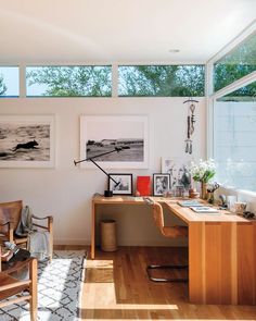 a home office with wooden desk and chairs in front of large windows overlooking the water