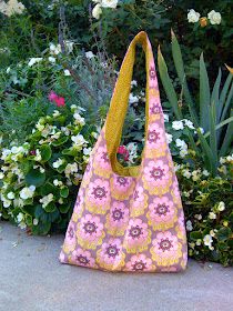 a pink and yellow flowered purse sitting on the ground next to some white flowers