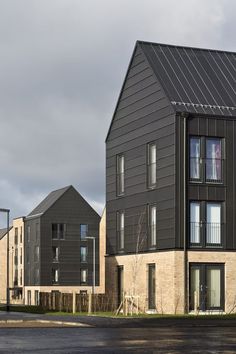 two buildings with balconies on the top and bottom floors, one has a black metal roof