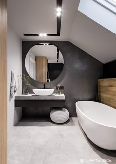 a large white bath tub sitting next to a bathroom sink under a skylight in a room