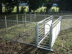 a fence that is in the middle of a field with grass and trees behind it