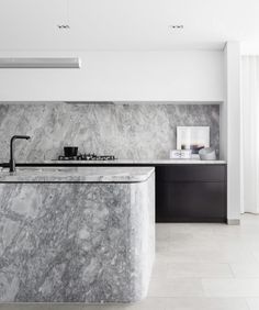 a kitchen with marble counter tops and black cabinets in the corner, along with an island