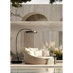 an outdoor seating area next to a pool with white pillows on it and a black floor lamp