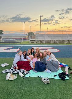 a group of young women sitting on top of a green field next to each other