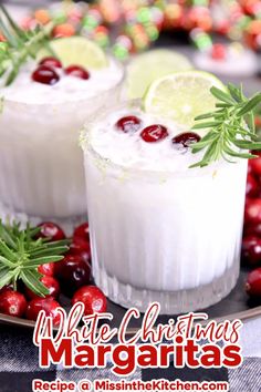 white christmas margaritas on a plate with cranberries and rosemary garnish