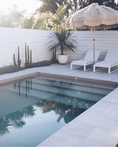 an empty swimming pool with lounge chairs and umbrella