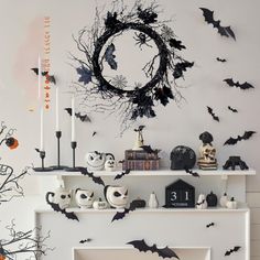 a fireplace with halloween decorations on it and bats hanging from the mantles in front