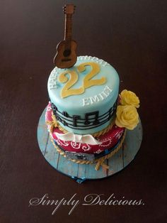 a birthday cake with a guitar on top and flowers around the edges that says twenty