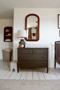 a baby crib with a mirror above it and a dresser in front of it