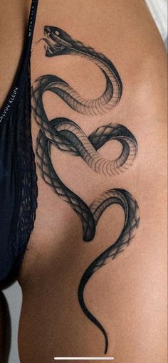 a woman's back with a snake tattoo on it